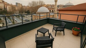 A balcony with two chairs and a table, overlooking a parking lot and cityscape with historic buildings. - Center Port Hotel Karaköy (Istanbul)