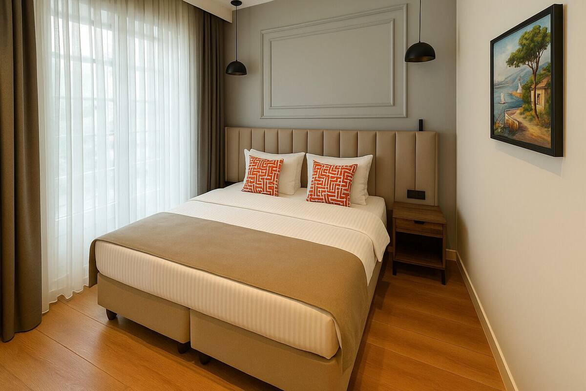 A neatly arranged bedroom with a large bed, two bedside tables, a painting on the wall, and a window with curtains.
