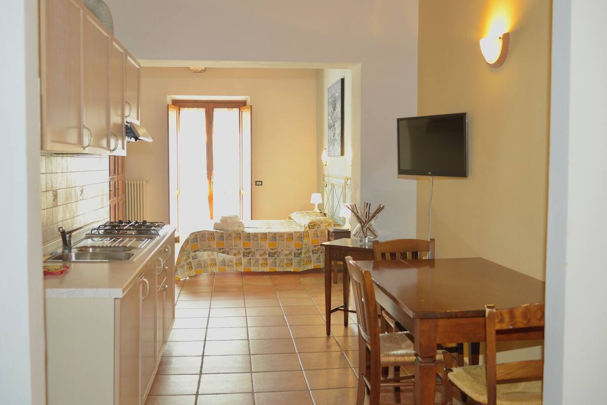 Une cuisine de taille réduite comprenant une cuisinière, un évier et un coin repas avec des chaises et une table.