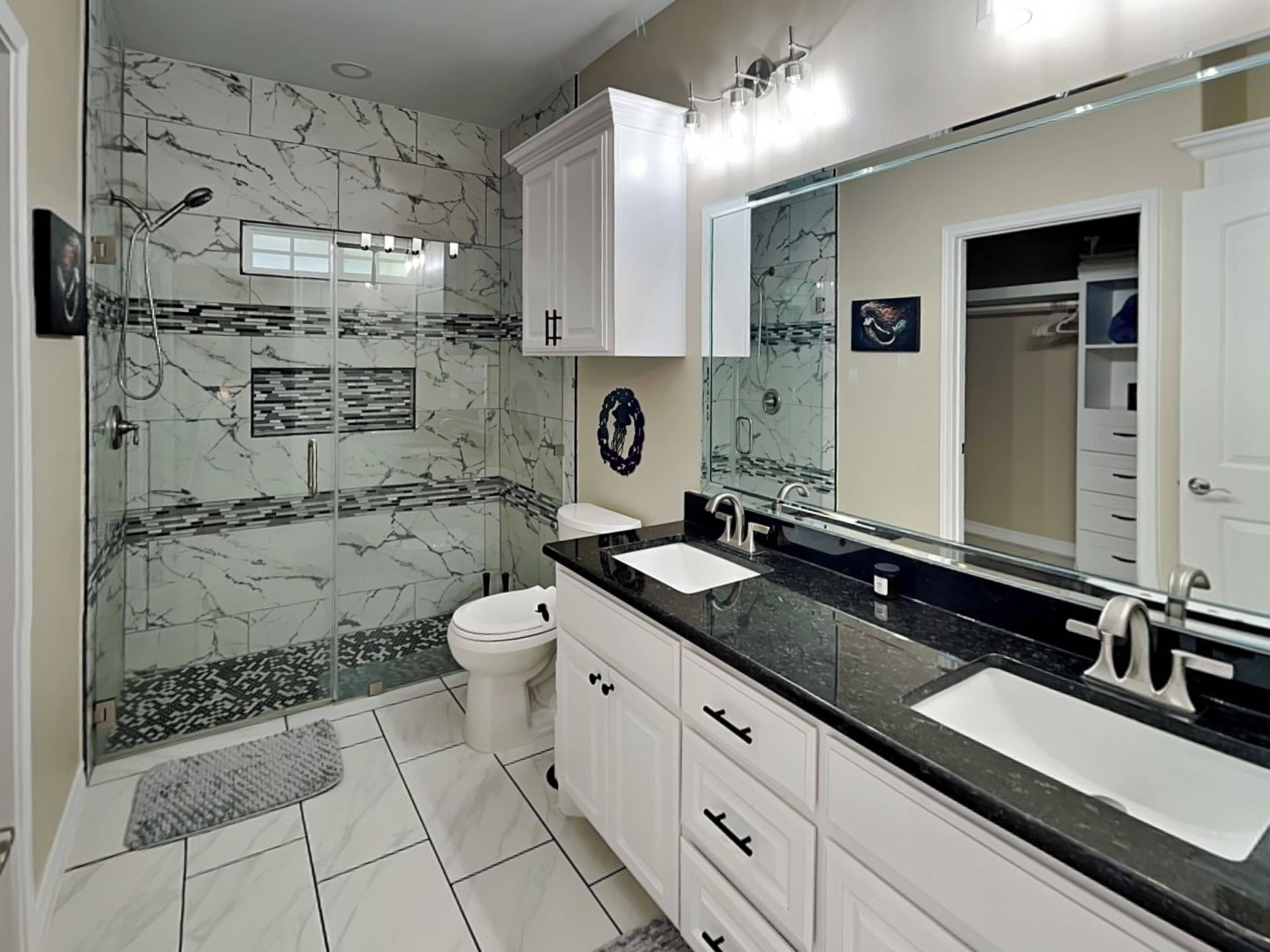 Un baño moderno con dos lavamanos, cabina de ducha de cristal y un espejo grande.