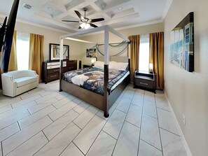 Une chambre à coucher avec un lit à baldaquin, un ventilateur de plafond, une table de chevet, une commode et une chaise.