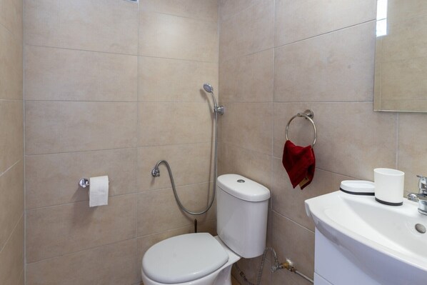A bathroom with a toilet, a shower, and a sink.