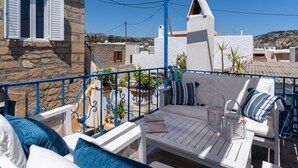 Ein Balkon mit weißen Möbeln, darunter eine Couch und ein Tisch, sowie ein blaues Geländer.