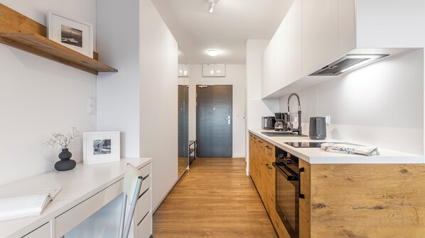 A modern kitchen with white cabinetry, a wooden countertop, and a built-in stove.