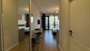 Habitación de hotel con cama, escritorio y silla. Se ve una ventana con vistas a edificios.
