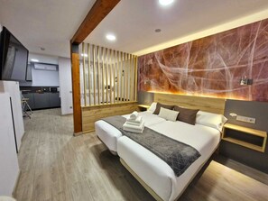 A modern hotel room with a large bed, wooden headboard, and a marble-patterned wall. - Feeling Home - Suites&Rooms (Leon)