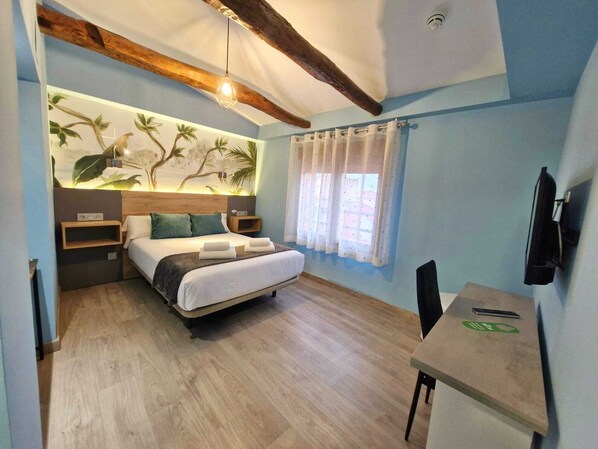 A bedroom with a bed, bedside tables, a desk, a television, and a mural on the wall. - Feeling Home - Suites&Rooms (Leon)