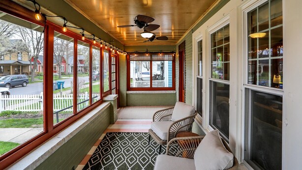 Eine überdachte Veranda mit Deckenventilator, gemustertem Boden und Korbstühlen.
