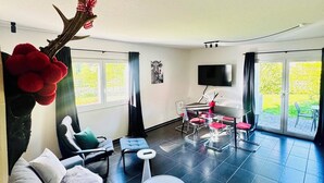 A modern living room with a sofa, a coffee table, and a dining area with a TV. - Forest Soul (Feldberg) - Terrace (Feldberg (Schwarzwald))