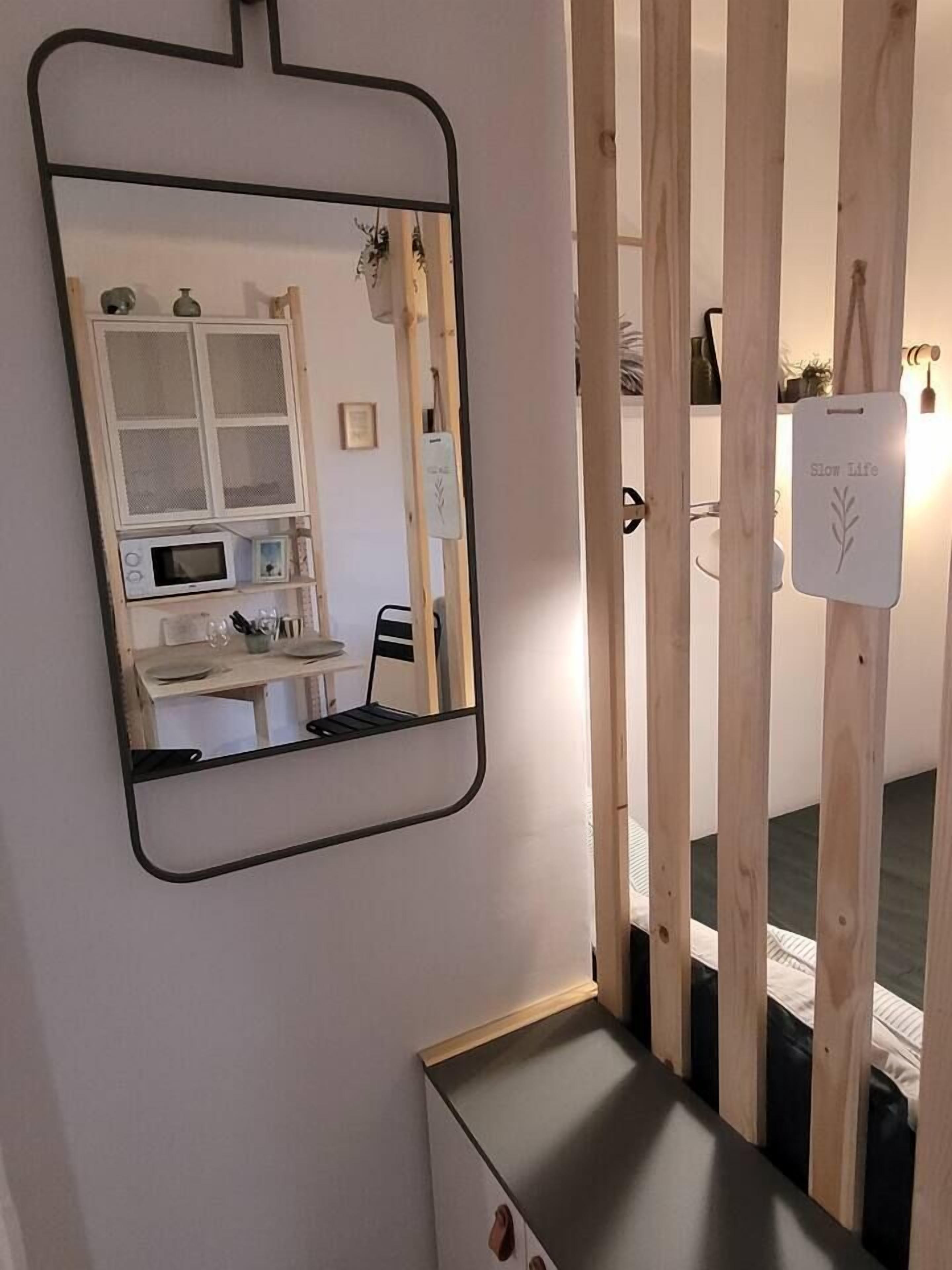Une pièce avec un grand miroir, une cloison en bois et un lit.