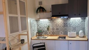 A compact kitchen with a wooden table, a sink, and a microwave. - Cocooning apartment Air-conditioning / near center / Parking (Hyères)