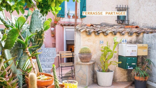 A courtyard with potted cacti and succulents, a metal bench, and a mailbox with numbers 48 and 50. - Cocooning apartment near the sea (Carqueiranne)