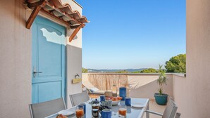 A balcony with a table set for breakfast, a blue door, and a view of the landscape. - Le toit du Port : Terraces/Pool/Clim/Parking (Hyères)