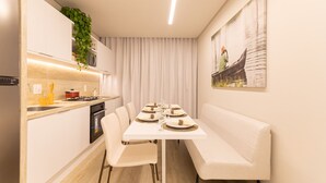 A modern kitchen with a dining area, white cabinetry, a built-in oven, and a dining table set for six. - Riverside HOUSI by Carpediem em Recife (Recife)