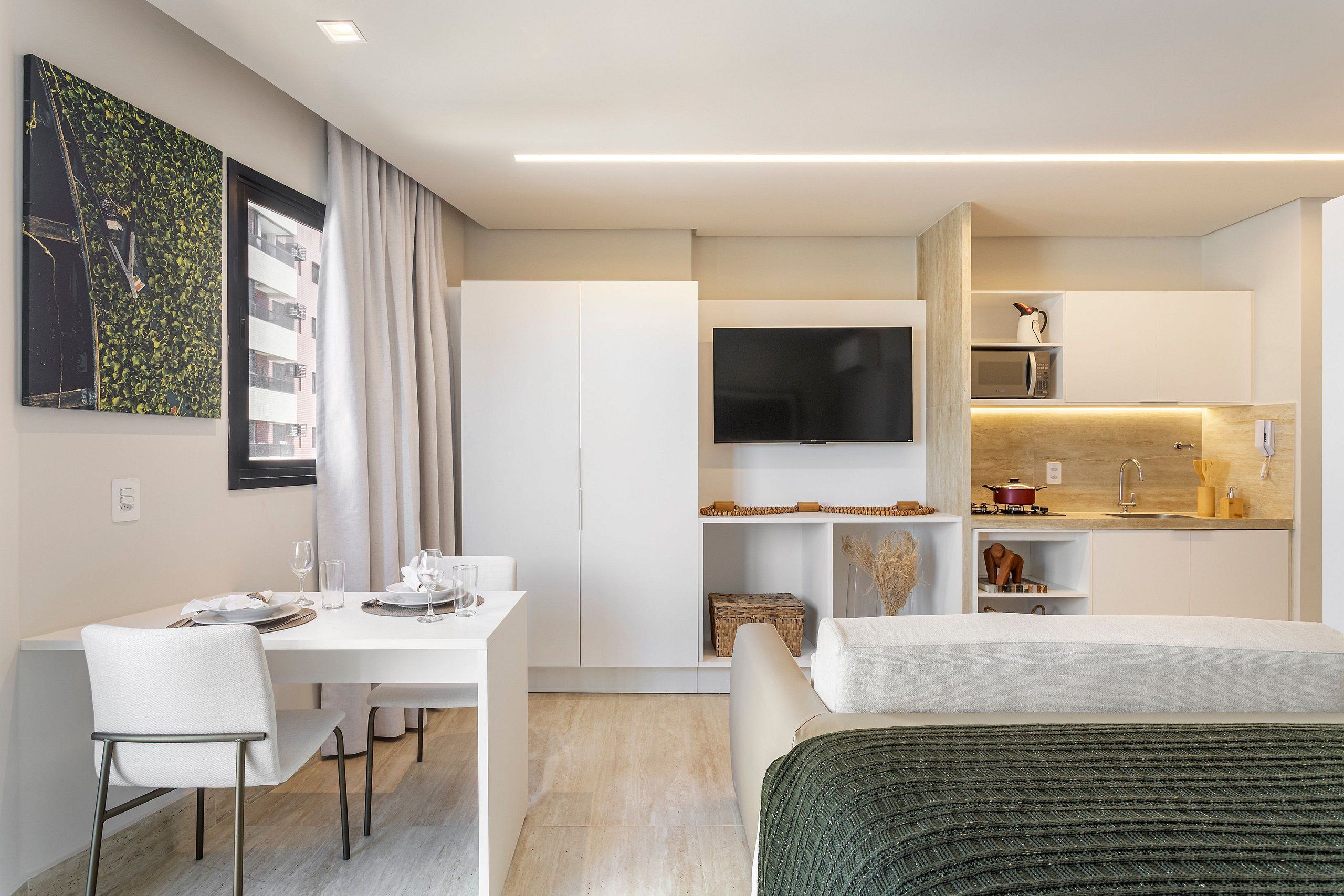 Una habitación de hotel moderna con comedor, kitchenette y un televisor grande.