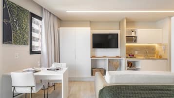 Una habitación de hotel moderna con comedor, kitchenette y un televisor grande.