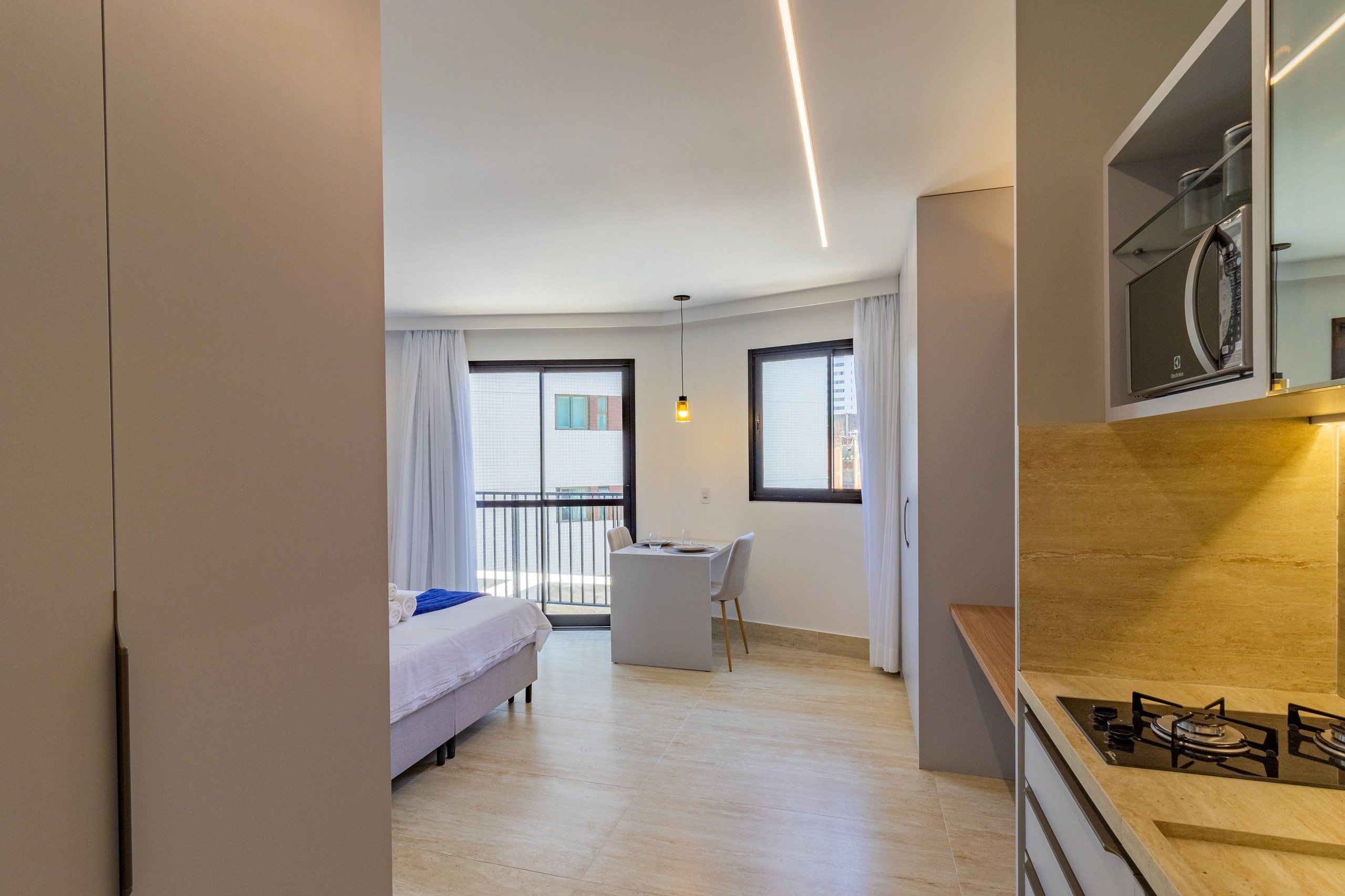 Ein modernes Hotelzimmer mit einem Bett, einem kleinen Tisch und einer Küchenzeile.