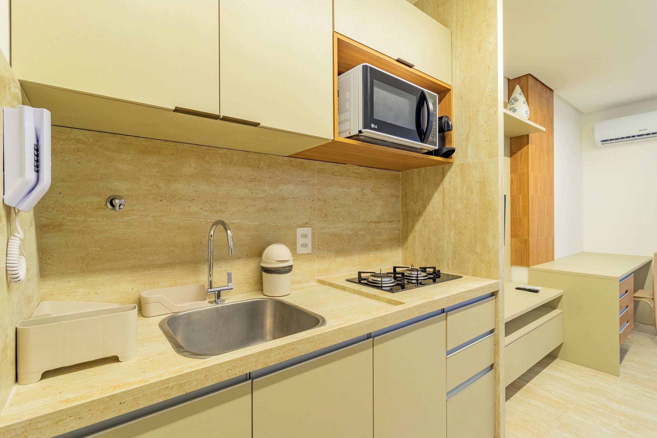 Una cocina compacta con lavamanos, estufa, microondas y armarios.
