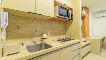 A compact kitchen with a sink, stove, microwave, and storage cabinets.