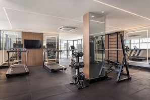 A modern gym with treadmills, a weight bench, and a mirrored wall. - Riverside HOUSI by Carpediem em Recife (Recife)