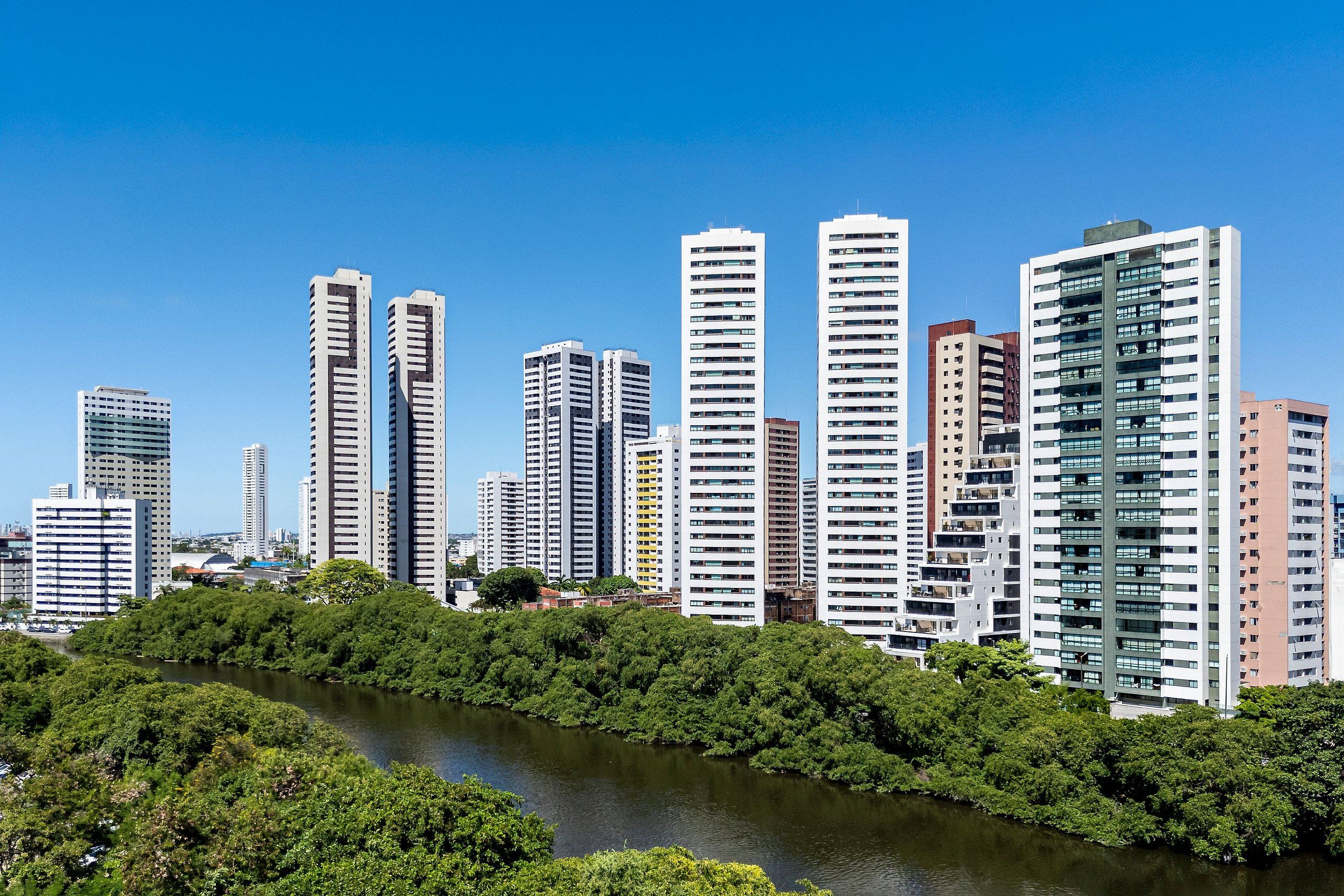 A cityscape with high-rise buildings and a river in the foreground.