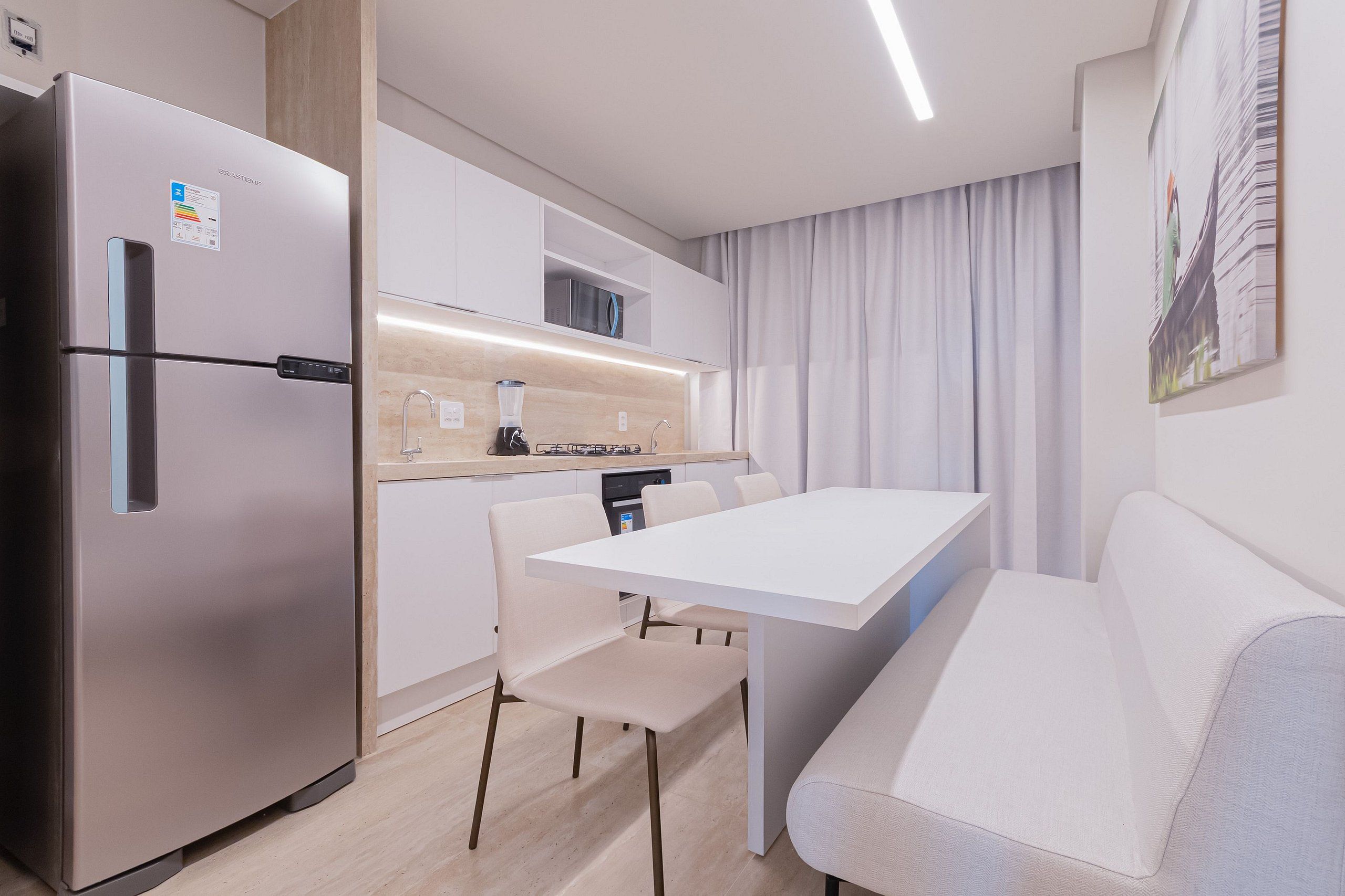 Una cocina moderna con refrigerador integrado, una mesa de comedor con sillas y un sofá.