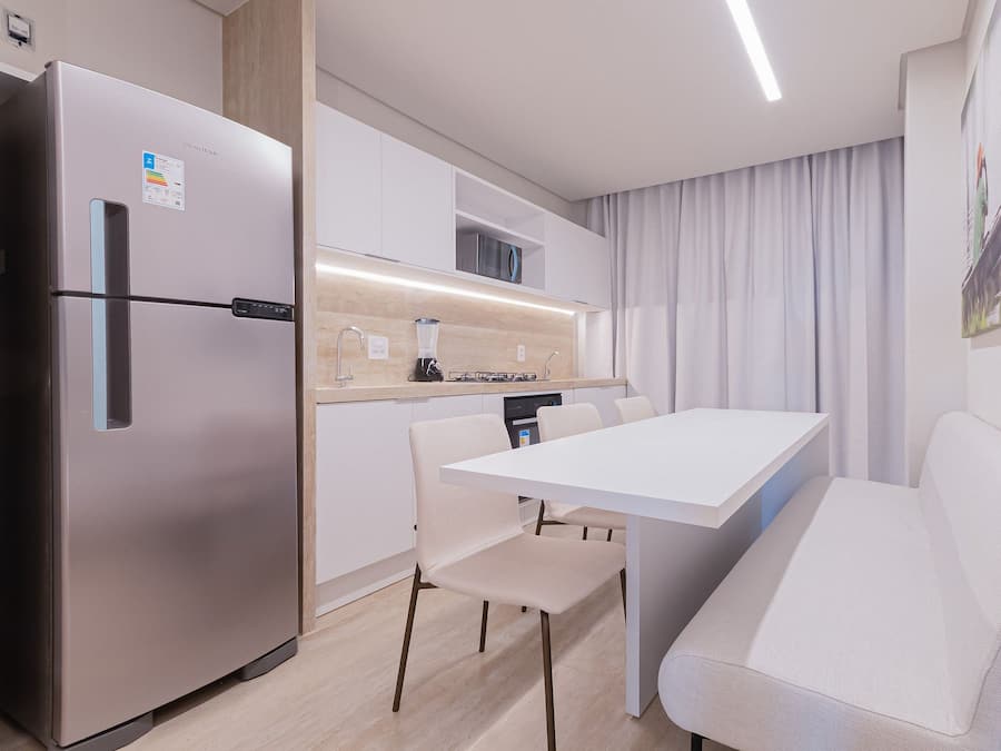 Una cocina moderna con refrigerador integrado, una mesa de comedor con sillas y un sofá.