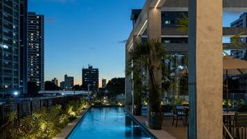 Una piscina con vistas a un paisaje urbano, rodeada de edificios modernos y palmeras.