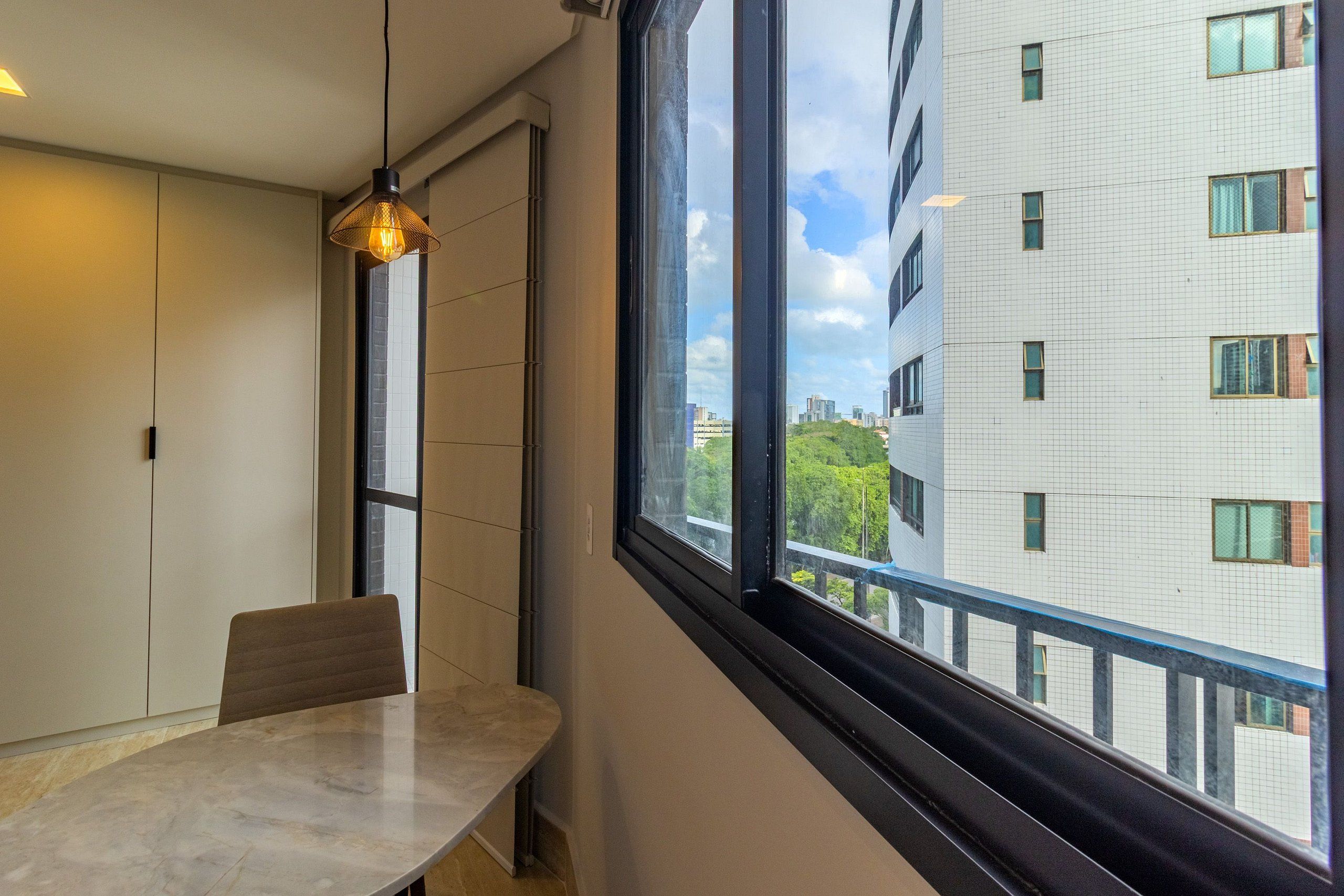 Una habitació moderna amb una finestra gran, una taula de dinar i un llum penjant.