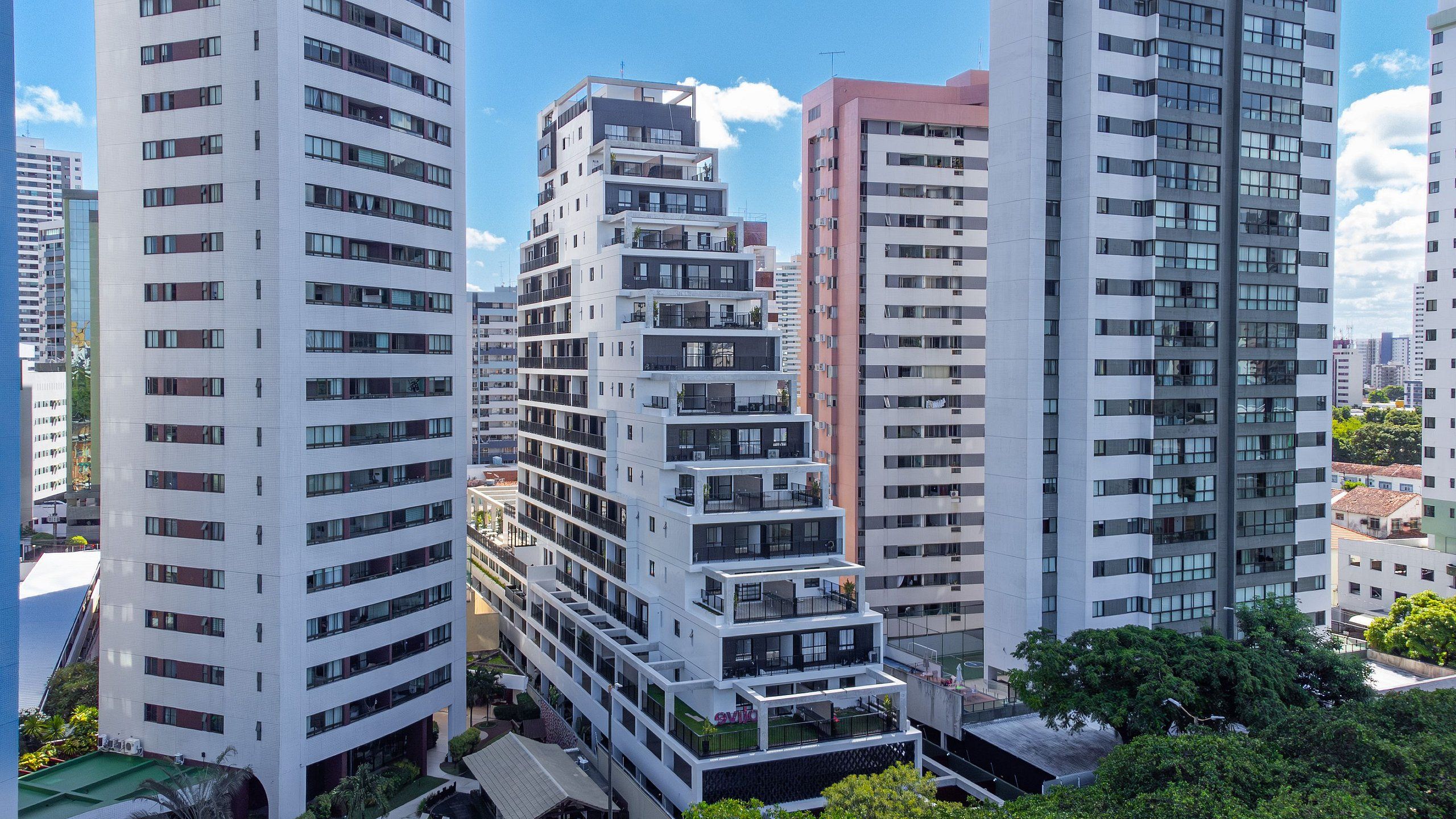 A modern high-rise building with multiple balconies and a central courtyard.