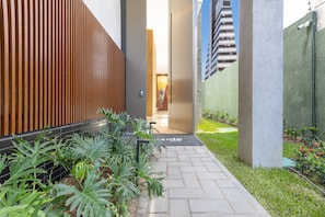 A pathway leading to a building entrance with a wooden fence, a concrete pillar, and a green wall. - Riverside HOUSI by Carpediem em Recife (Recife)