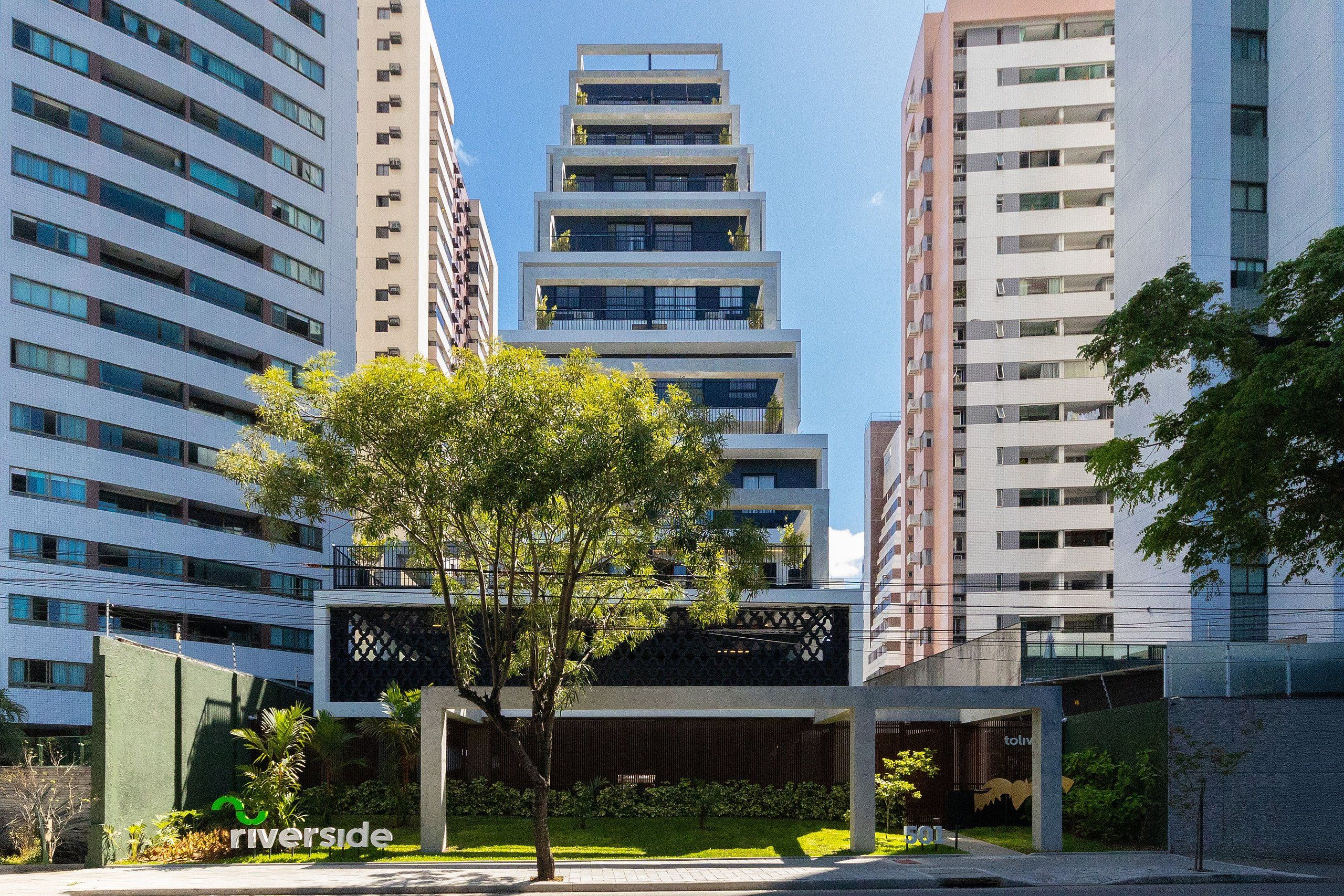 A modern building with multiple floors, large windows, and a central courtyard with a tree.