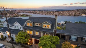 A large, two-story house with a prominent front porch and a large tree in front. - High-end city home loaded with amenities! (Seattle)