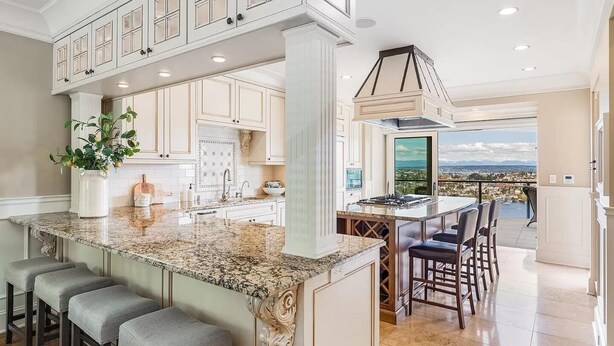 A spacious kitchen with a granite countertop, bar stools, and a view of the city. - High-end city home loaded with amenities! (Seattle)
