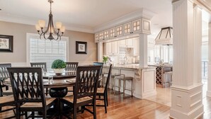 A dining area with a wooden table and chairs, a chandelier, and a view into the kitchen. - High-end city home loaded with amenities! (Seattle)