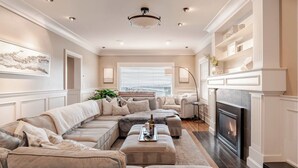 A spacious living room with a large sectional sofa, a fireplace, and a city view through the window. - High-end city home loaded with amenities! (Seattle)