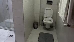 Un baño pequeño con azulejos, un inodoro, zona de ducha y un perchero para toallas.