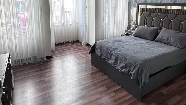 Un dormitorio moderno con una cama grande, suelo de madera y una araña.