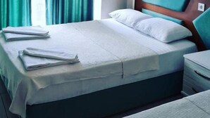 A neatly made bed with pillows and folded towels, a nightstand, and a window with curtains. - Richard place otel apart (Marmaris)