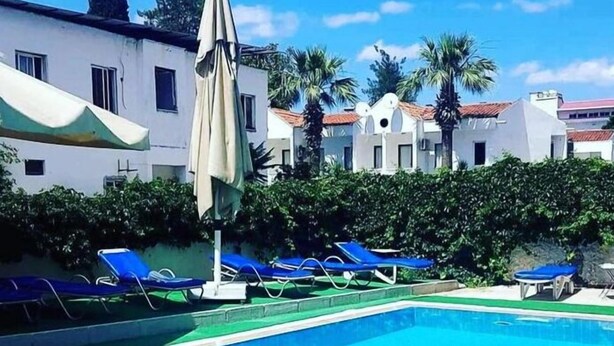 A swimming pool with blue water, surrounded by lounge chairs and umbrellas. - Richard place otel apart (Marmaris)