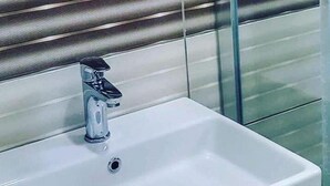 A bathroom with a modern sink, a mirror, and striped wall panels. - Richard place otel apart (Marmaris)