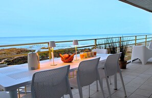 A terrace with a table set for dining, overlooking a rocky coastline. - the blue parenthesis - face mer (Les Sables-d´Olonne)
