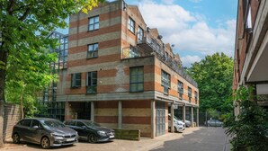 Un immeuble à plusieurs étages avec une façade en briques, une entrée de garage et des voitures garées.