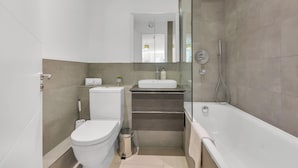Une salle de bain moderne équipée de toilettes, d’un lavabo et d’une baignoire.