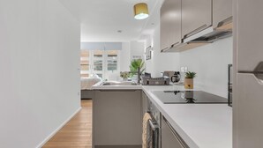 Une cuisine moderne avec des meubles de couleur grise, un îlot central et un luminaire suspendu.