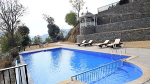 A swimming pool with lounge chairs and a stone wall.