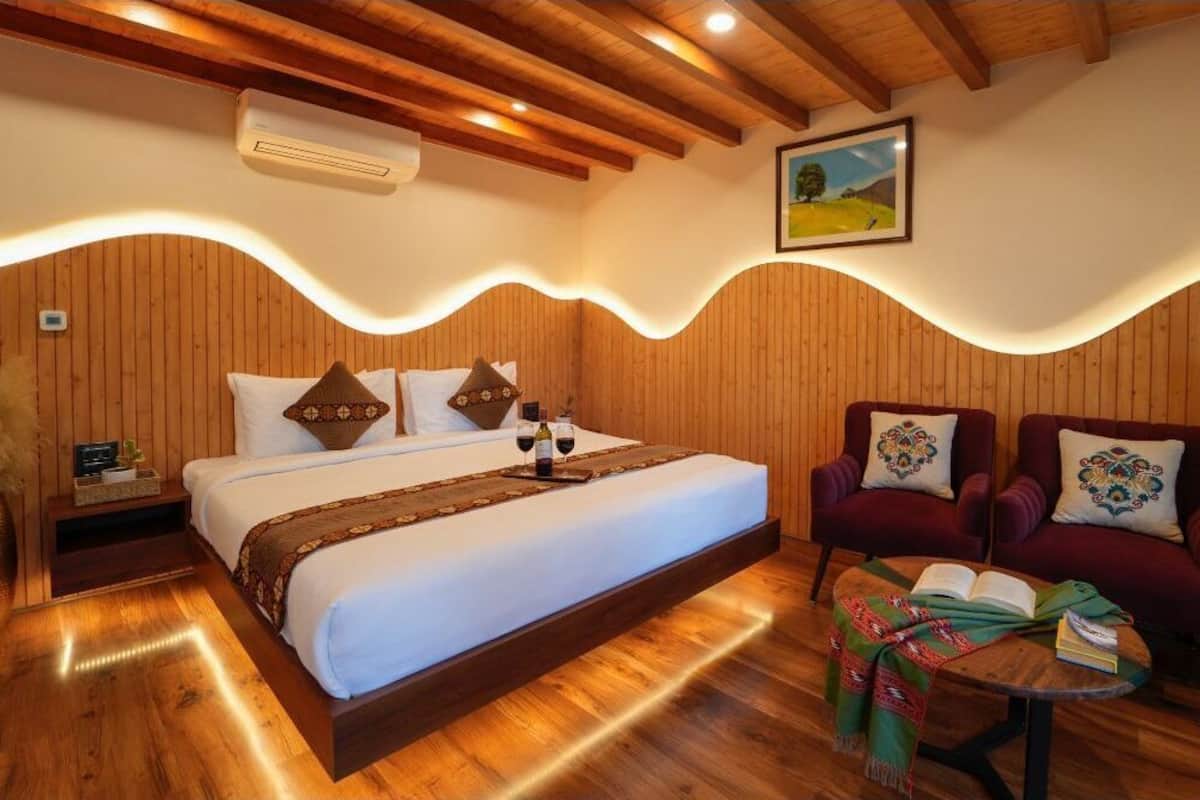 Een kamer met houten lambrisering, een bed, twee fauteuils, een tafeltje en een schilderij aan de muur.