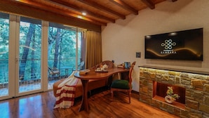 A cozy room with a wooden dining table, a fireplace, and a large window overlooking a forest. - Samsara Luxury Cottages & Spa  (Kandaghat)