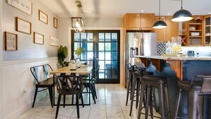 Una cocina moderna con una isla central, taburetes de bar y un comedor con sillas.