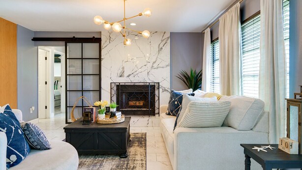 Una sala de estar moderna con chimenea, un sofá, una mesa de centro y una araña.